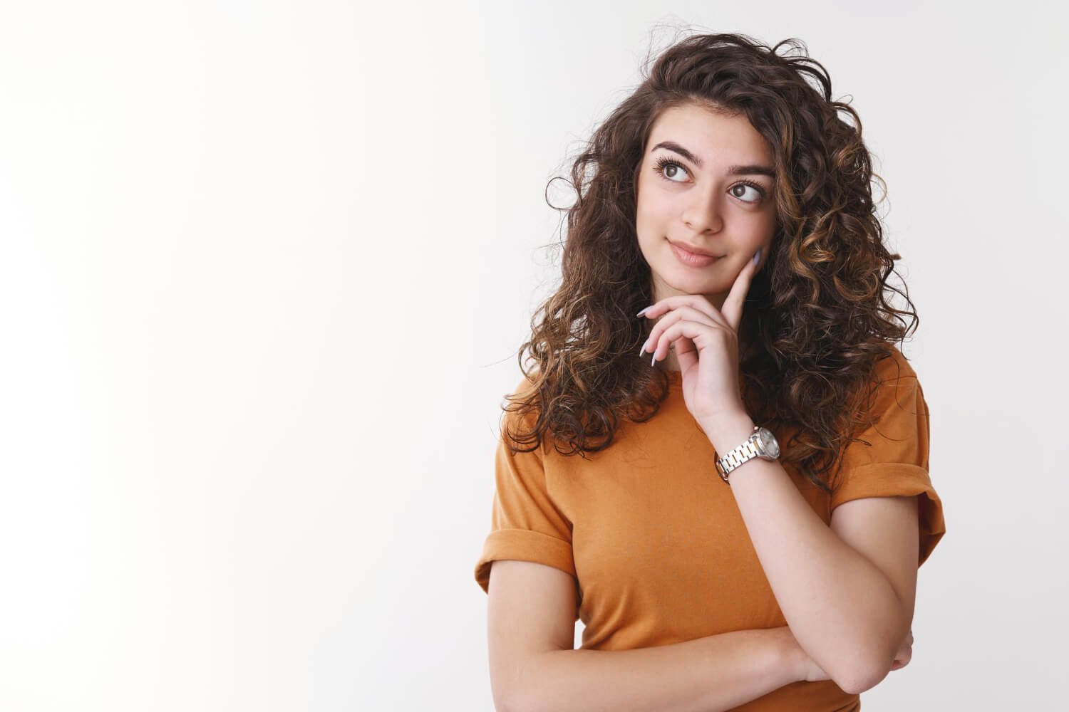 Mulher jovem de cabelos cacheados em pose pensativa, refletindo sobre o tratamento com implantes dentários sem dor em Campinas.