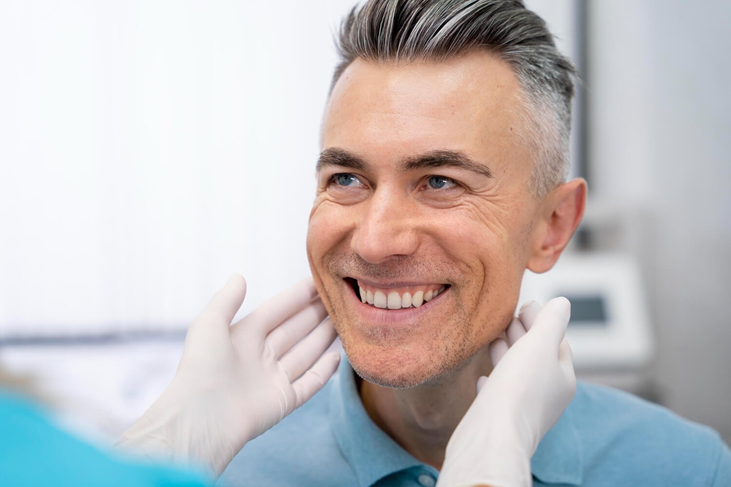 Homem adulto sorrindo feliz enquanto dentista examina seu rosto, avaliando opções de implante dentário e prótese protocolo em Campinas.