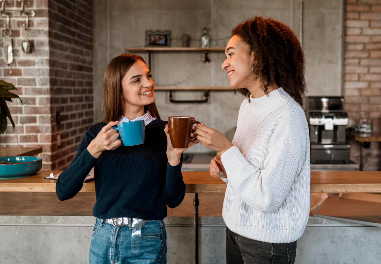 Duas jovens sorridentes tomando café juntas. Saiba se beber café mancha seu alinhador invisível na CC Freitas Odontologia em Campinas.